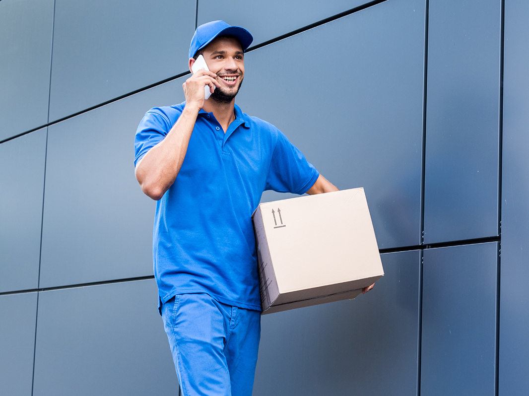 delivery man with cardboard box talking by phone
